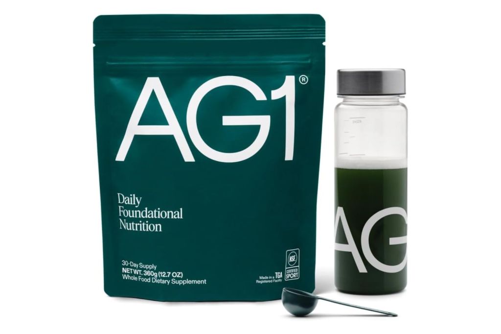 A pouch of AG1 next to a shaker with the product inside.
