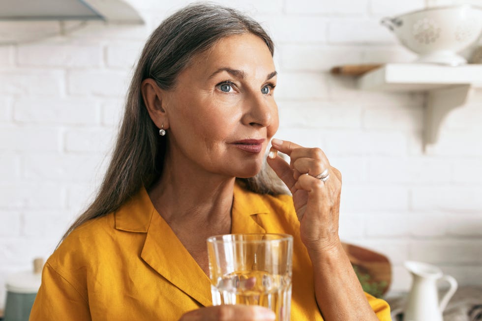 Cute mature female holding drugs and glass of water in hands. Elderly woman taking medication. Treatment course or vitamins complex idea. Healthy lifestyle and healthcare concept cute mature female holding drugs and glass of water in hands. elderly woman taking medication. treatment course or vitamins complex idea. healthy lifestyle and healthcare concept