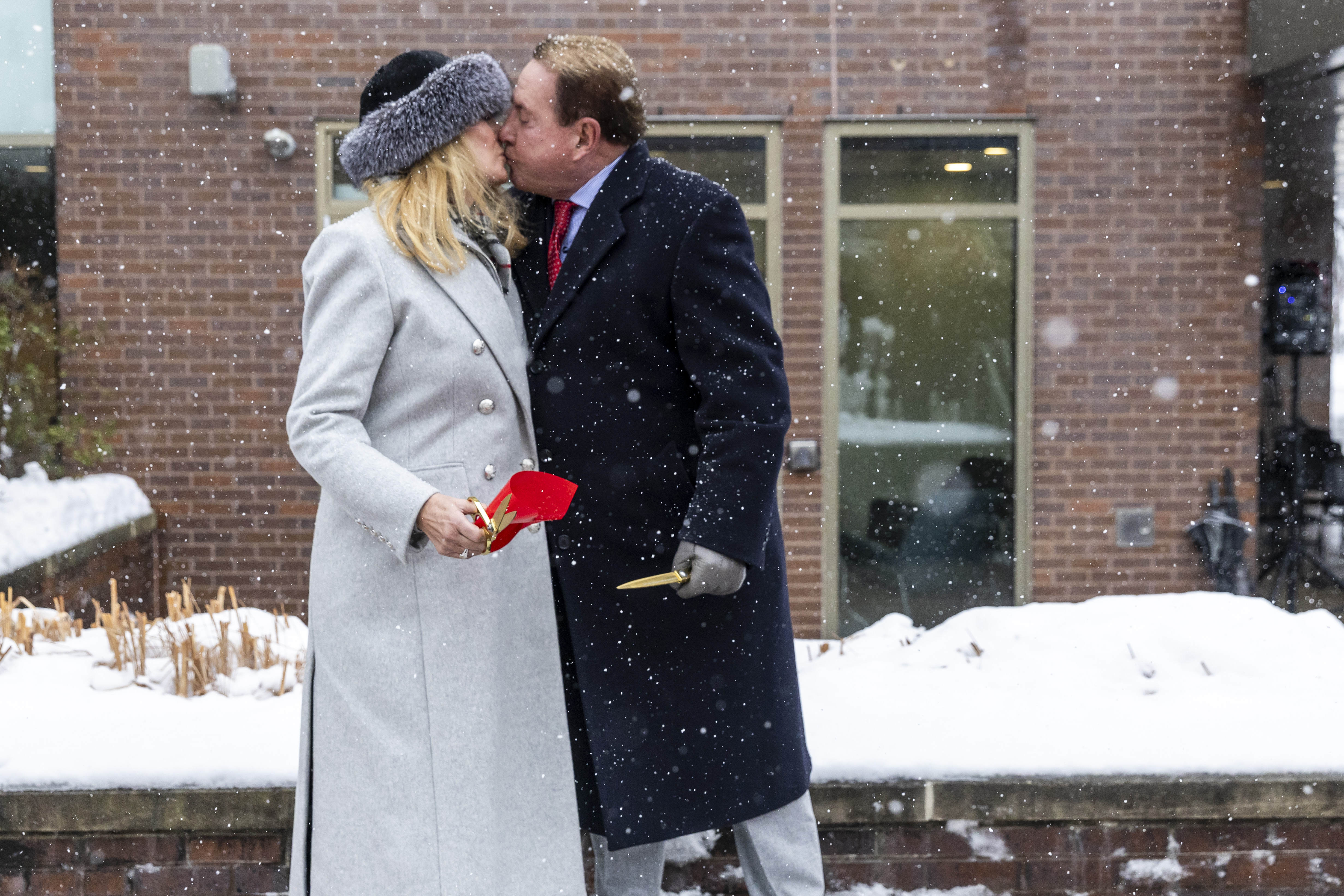 Kathryn, left, and Keith Klingenberg share a kiss after cutting a ribbon at a dedication ceremony held outside the newly named Keith and Kathryn Klingenberg Wellness Center at Davenport University in Grand Rapids, Mich. on Wednesday, December 10, 2025.
