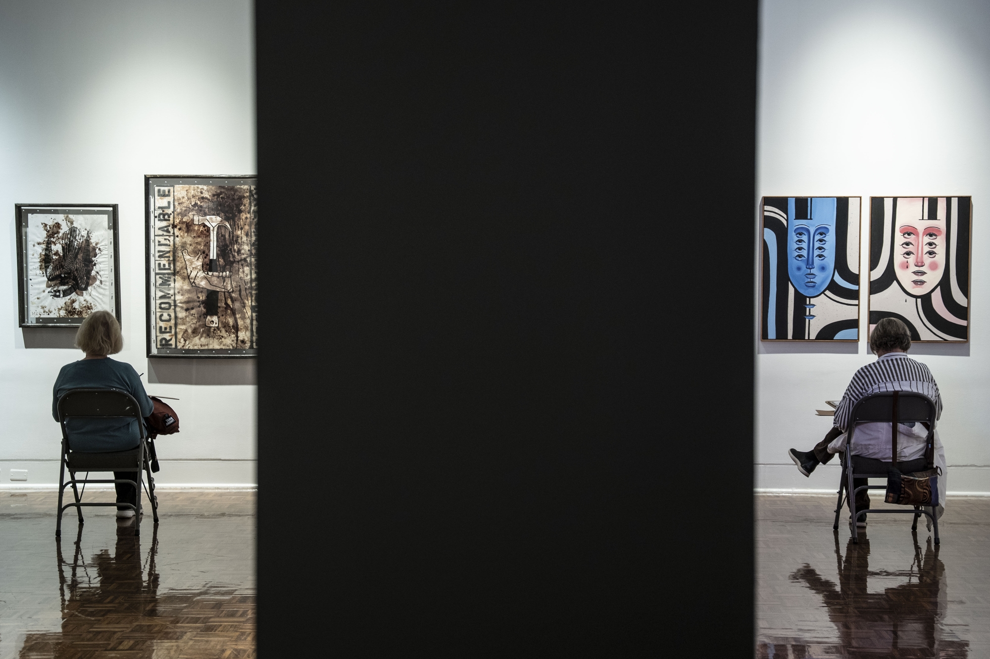 Peggy Newell and Sue Purdy sketch paintings hung up on the wall of the MI: INK exhibit during the Sketching in the Galleries workshop hosted by the Flint Institute of Arts on Wednesday, Nov. 19, 2025. The workshop is part of their Creative Aging initiative.