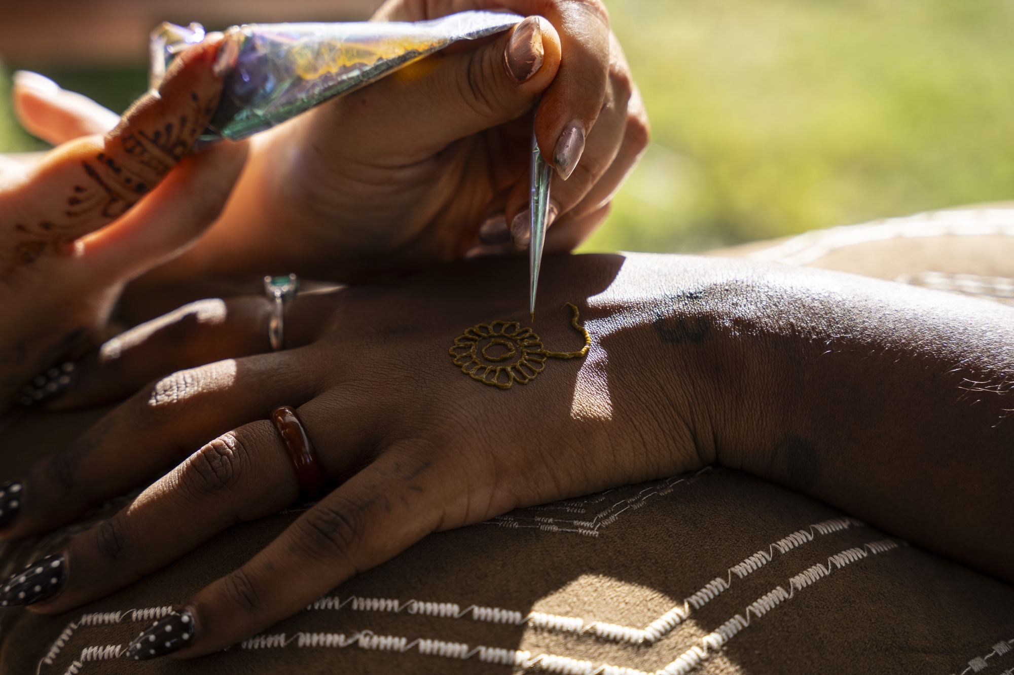 Nadia Alamah gives a henna tattoo to Flint local Jelana Smith at Porch Fest in Flint on Friday, July 18, 2025. The event featured nearly 20 music artists and 45 vendors. 