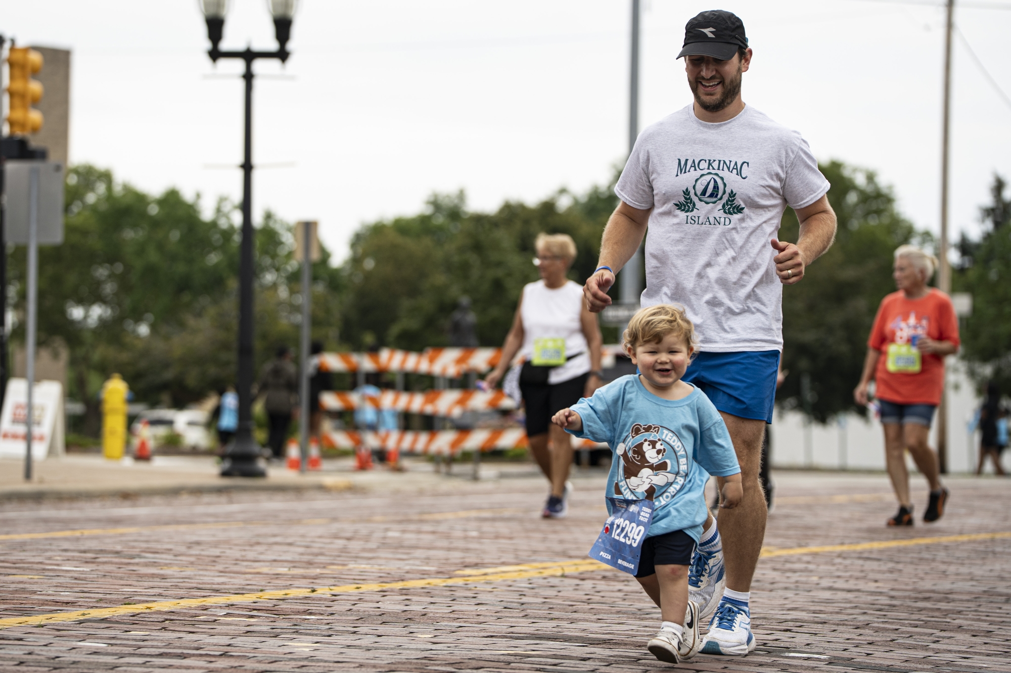 Spencer Irvin runs along with his son Paul, 2, in the Teddy Bear Trot during the 2025 HAP CareSource Crim Festival of Races on Saturday, Aug. 23, 2025 in Flint. Lukas Katilius | MLive.com