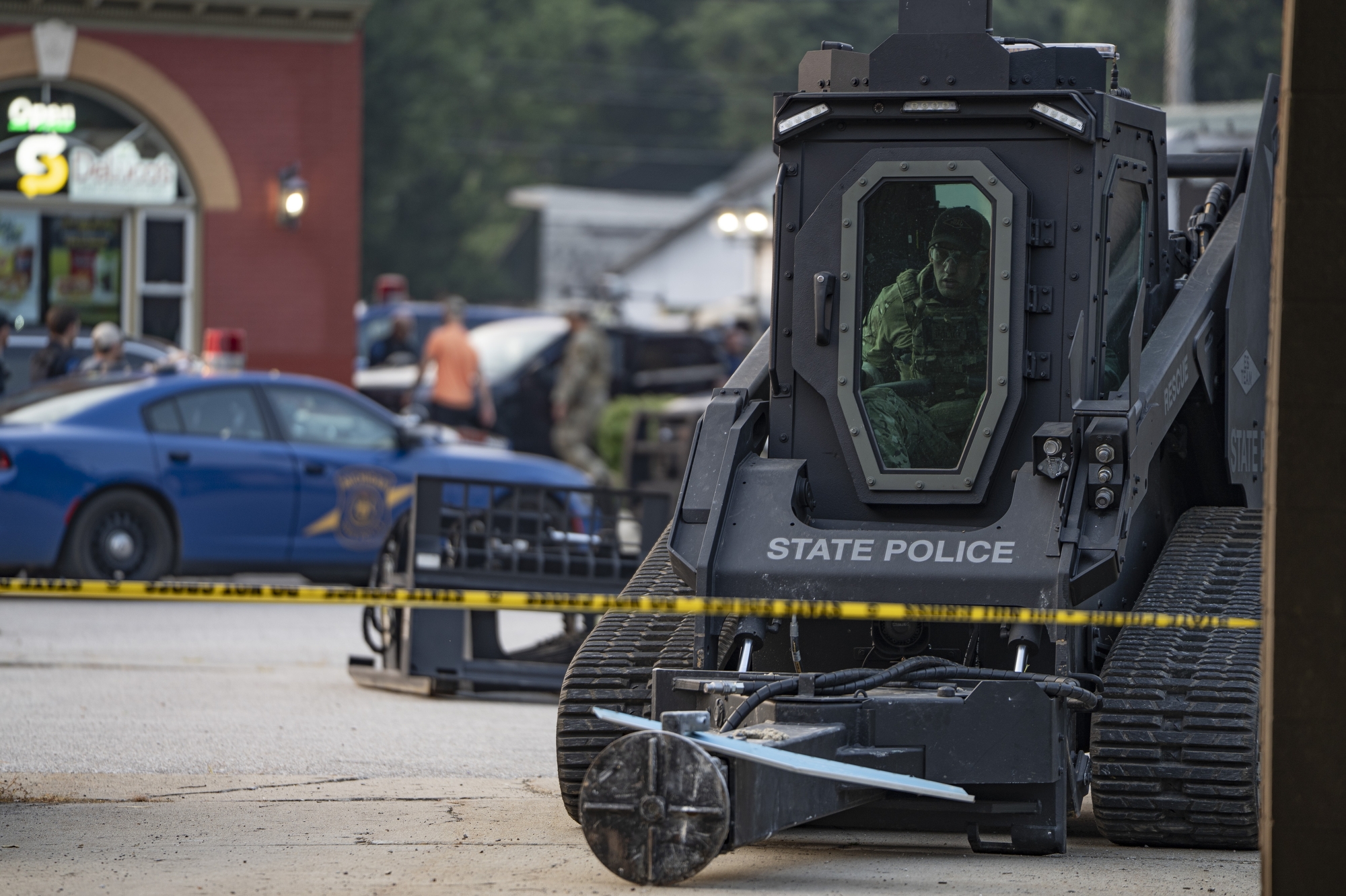 A Michigan State Police operator attaches a ram to his bulldozer as a man barricades himself inside of his home during a standoff with police forces in Otisville on Thursday, July 31, 2025. 