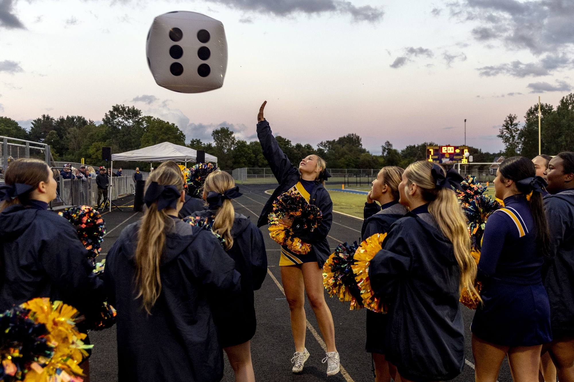 Goodrich cheerleaders hit a large inflatable die as they interact with the student section during the season-opening game on Thursday, Aug. 28, 2025 at Goodrich High School. Goodrich defeated Frankenmuth 17-14. (Jake May | MLive.com)