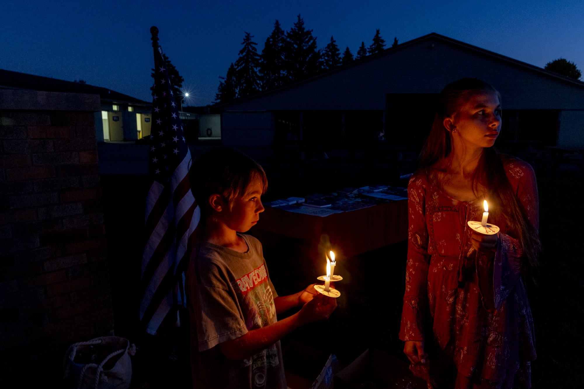 Phoenix Myers, 11 at left, and his sister Maryn, 16, join more than 100 people gathered for a vigil at dusk on Sunday, Sept. 28 at Holy Redeemer Church in Burton to honor Charlie Kirk, as well as the victims of the mass killing at the Church of Jesus Christ of Latter-day Saints in Grand Blanc Township, where four people were killed and multiple others were injured.