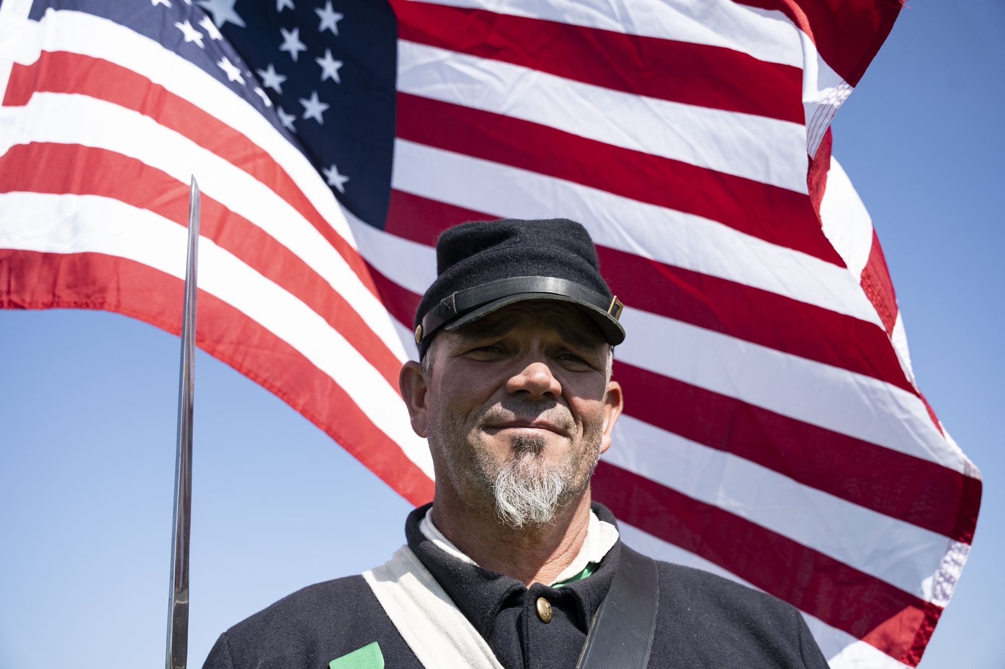 Eric Catz stands in front of the U.S. Union flag during the River of Time living history event at Johnson Pumpkin Farm in Saginaw on Saturday, Sept. 27, 2025. 