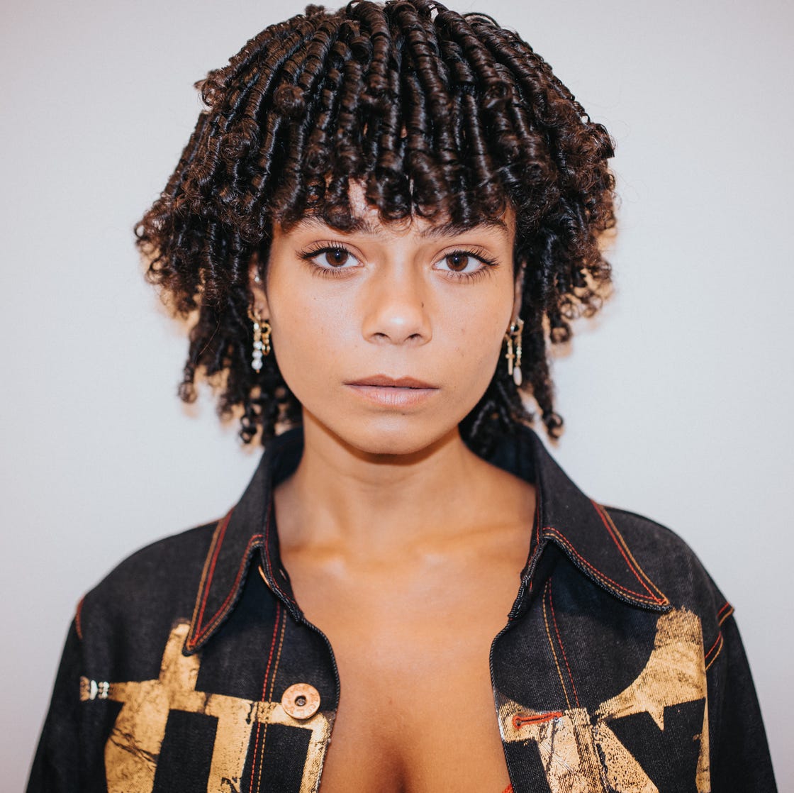 portrait featuring a person with curly hair wearing a patterned shirt