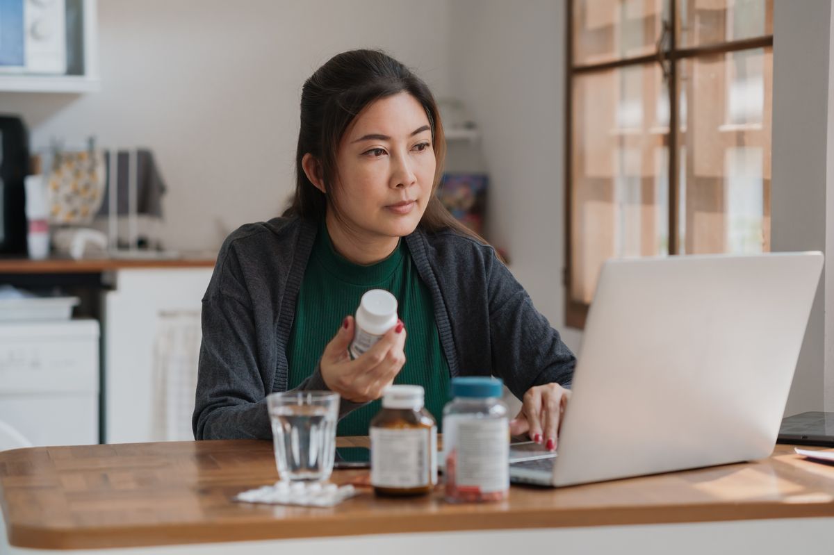 Woman holding tablets while looking at laptop