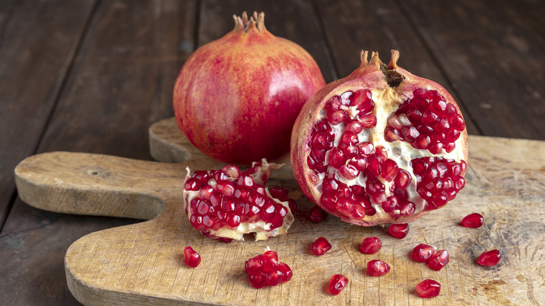 a halved pomegranate on a wooden board