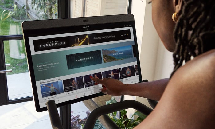 Person interacting with Peloton screen with Peloton user interface.