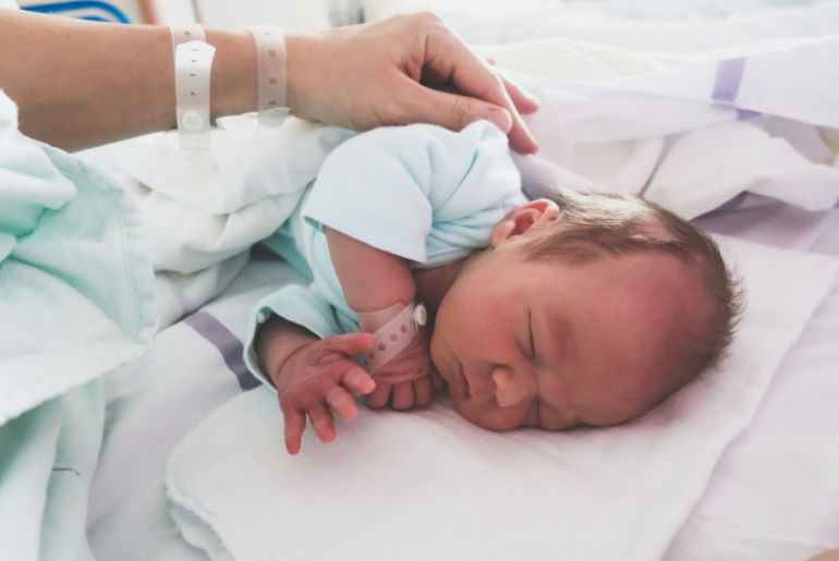 Mother and newborn resting after childbirth in maternity hospital room.