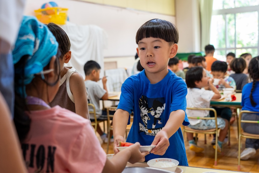 A young Japanese boy is served food in a childcare centre.