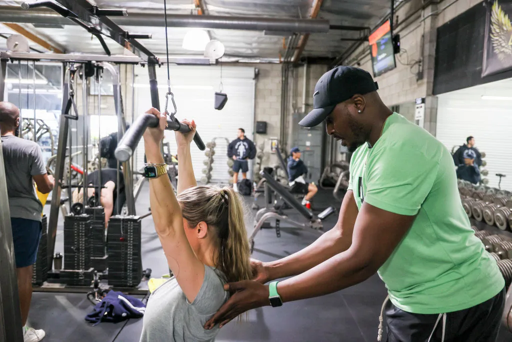 Woman being spotted on gym device
