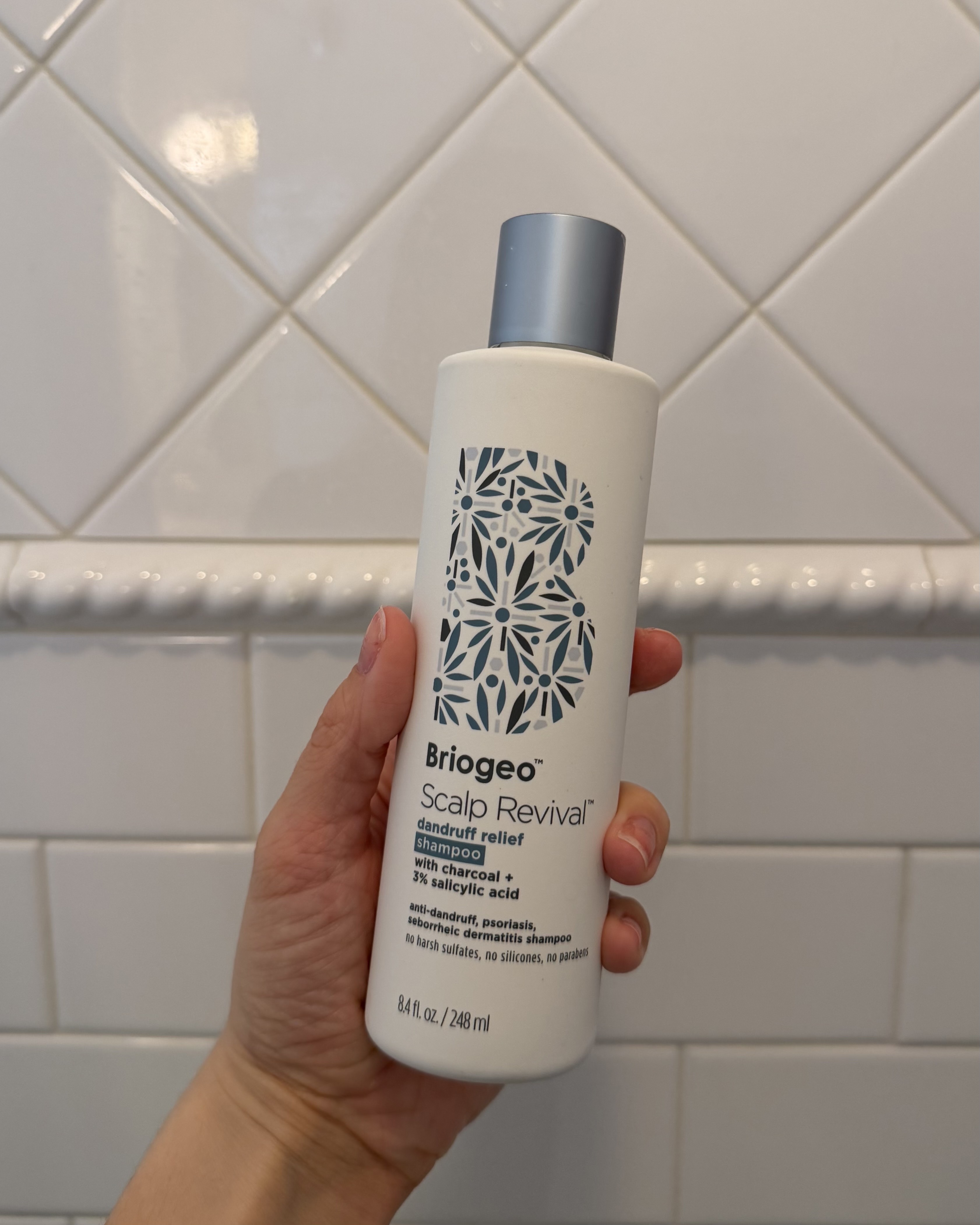 Brascia holding the Briogeo Scalp Revival Dandruff Relief Shampoo.
