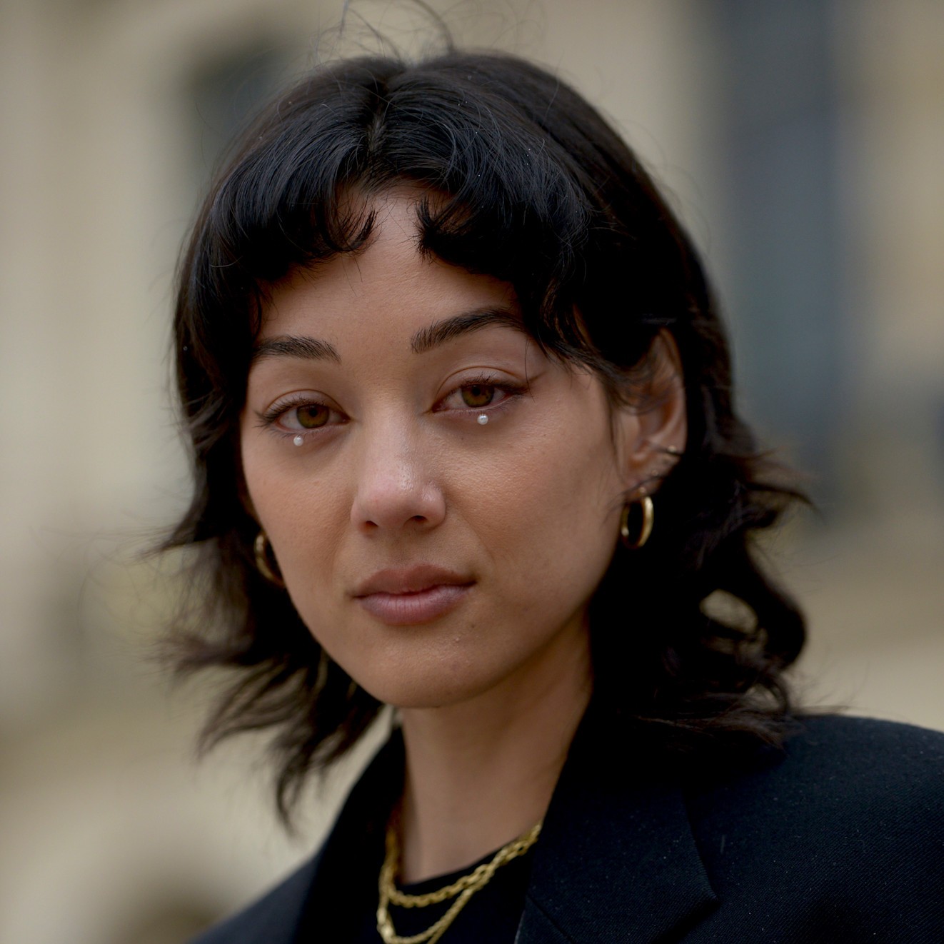A model wearing their hair styled with micro bangs that curve inward.