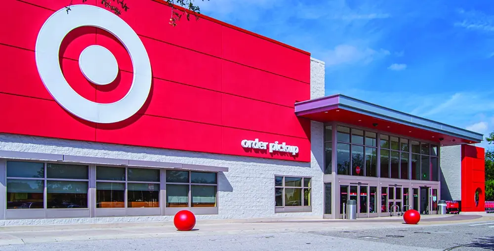 Exterior of a Target store with a bright red facade, large bullseye logo and an order pickup entrance under a blue sky.