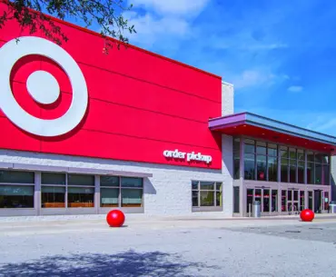 Exterior of a Target store with a bright red facade, large bullseye logo and an order pickup entrance under a blue sky.