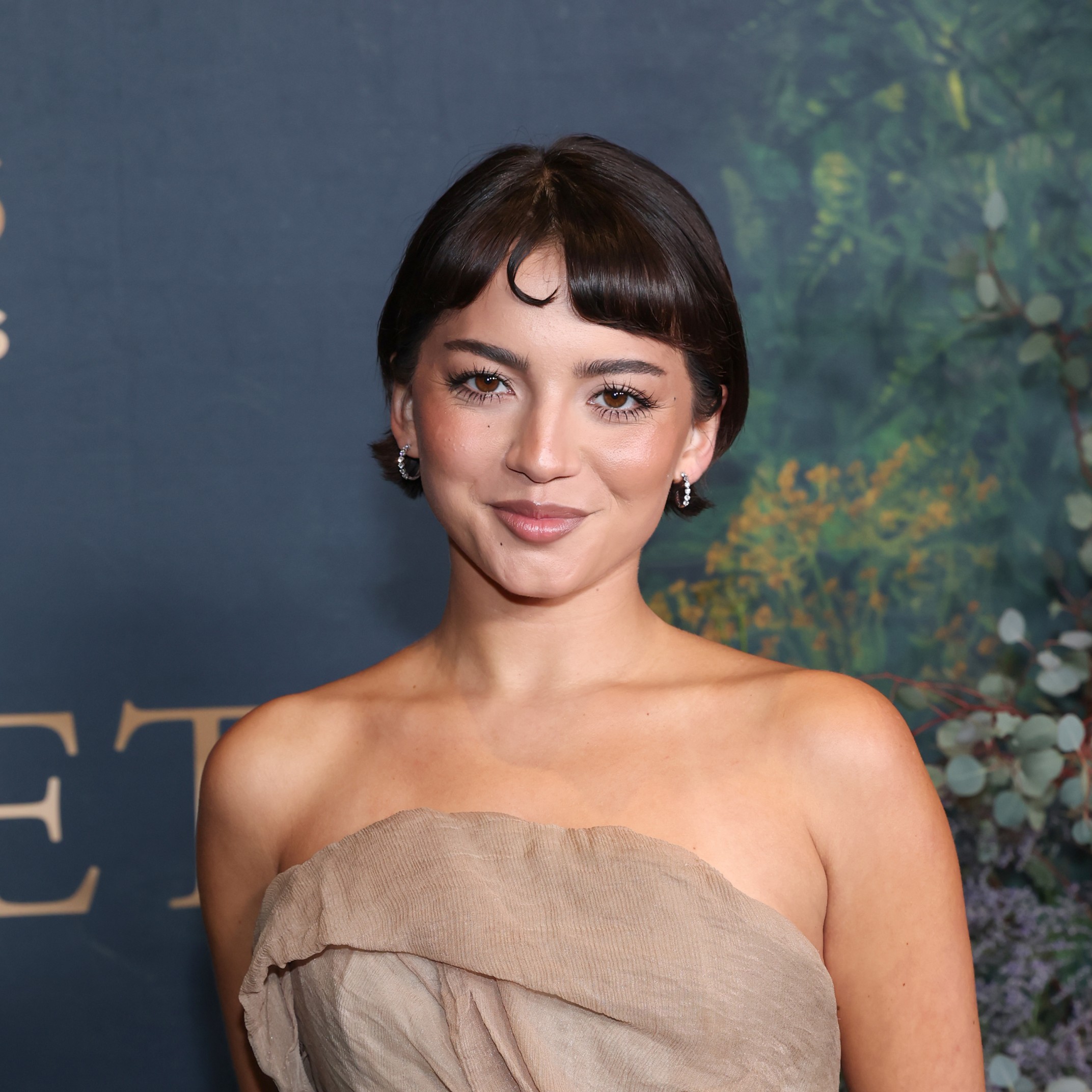 Isabela Merced with a vintage micro bang hairstyle featuring a single tiny curl.