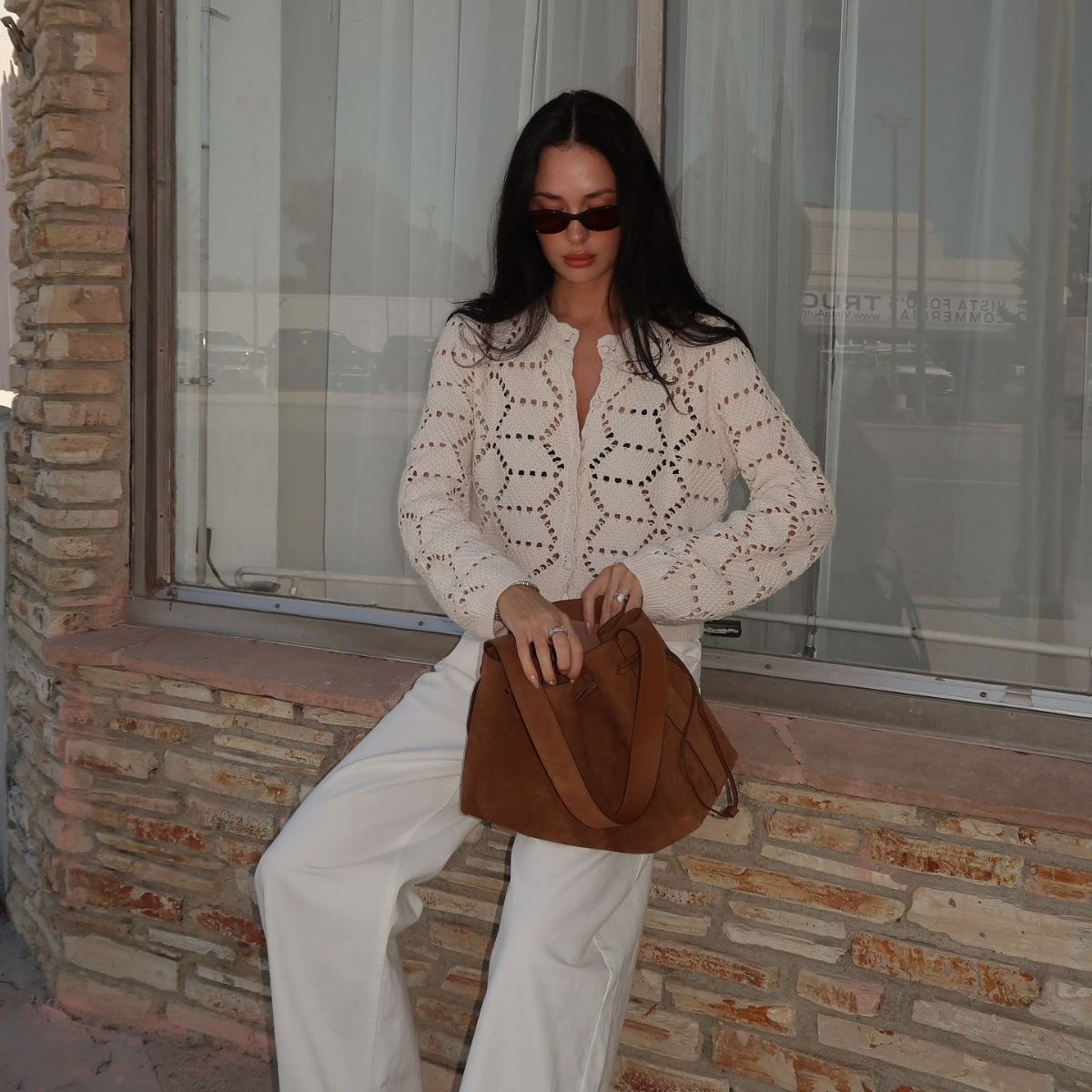 A woman sits on a ledge opening her bag