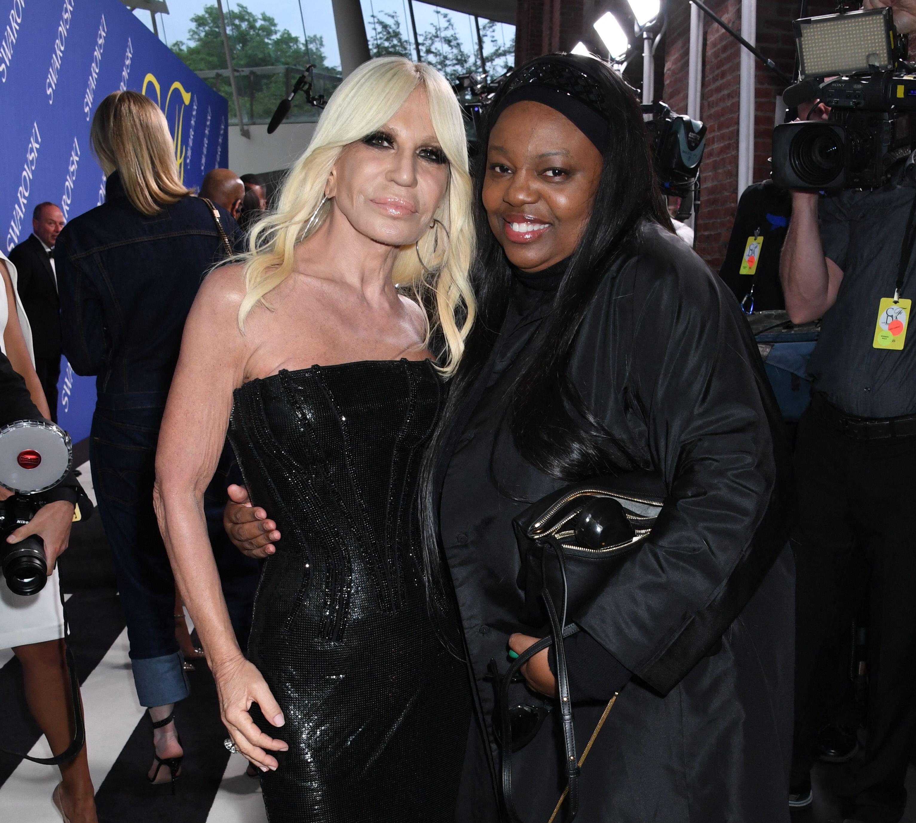 Donatella Versace and Pat McGrath pose for a photo at a cocktail reception.