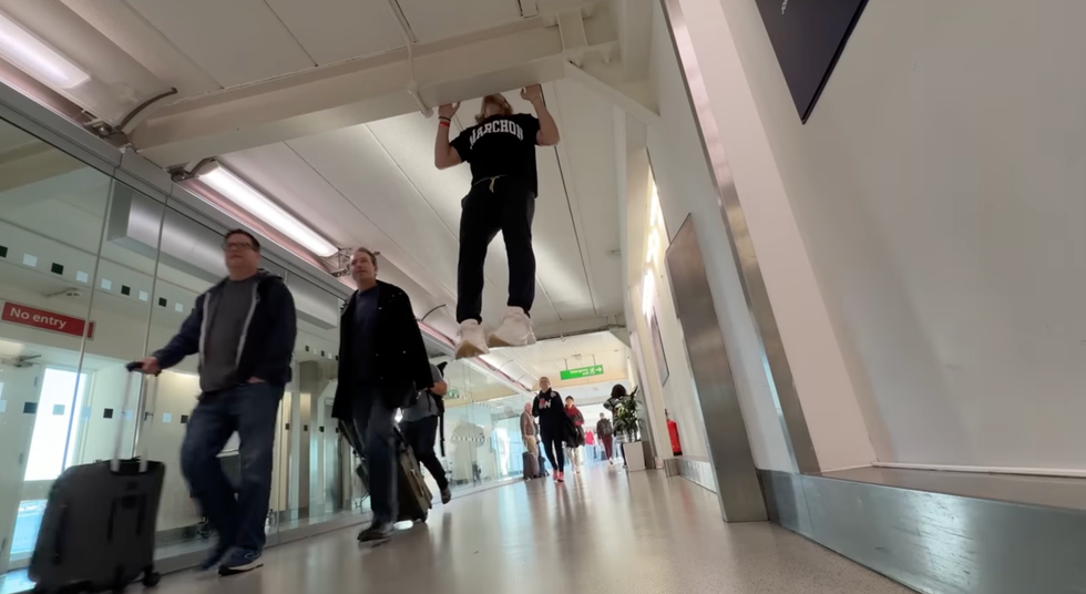 person performing pullups in an airport corridor