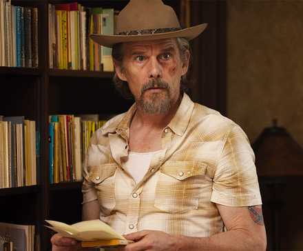 Lee Raybon (Ethan Hawke) with a bruised face and a hat, standing in front of bookshelves in 'The Lowdown'