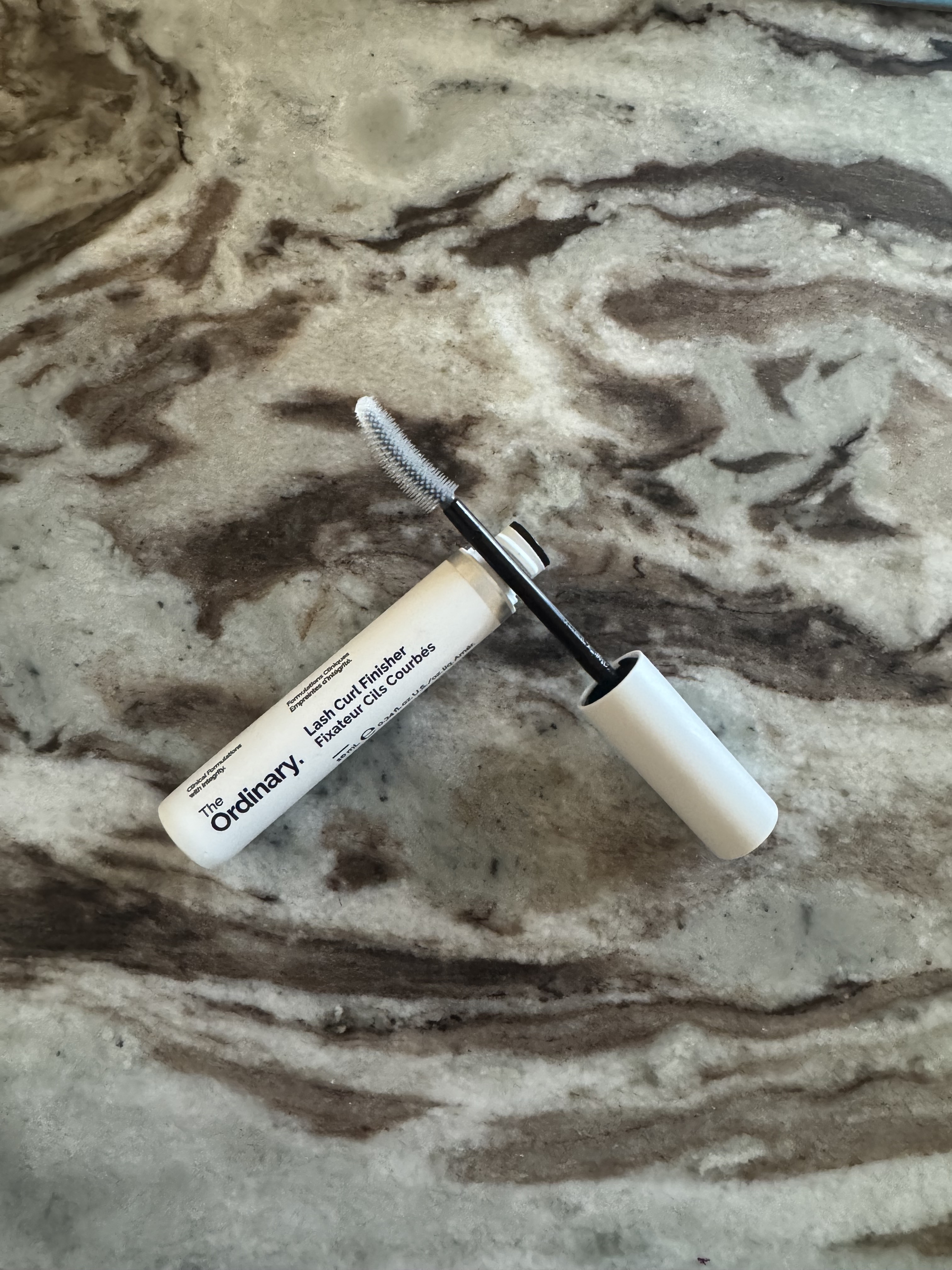 A photo of the ordinary lash curl finisher tube and wand on a marble surface
