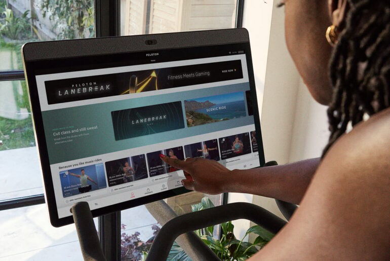 Person interacting with Peloton screen with Peloton user interface.