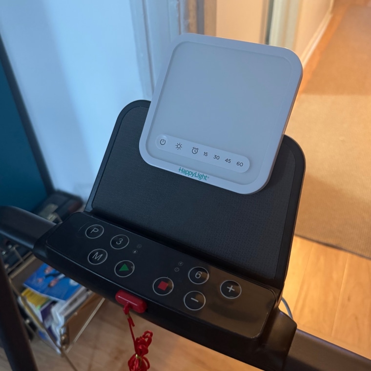 Photo of a VeriLux HappyLight Mini on the tablet stand of a walking pad.