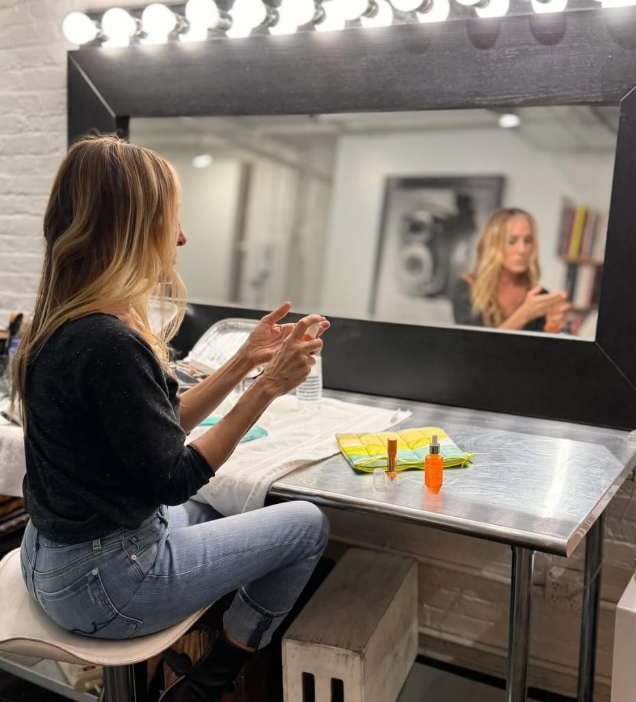 Sarah Jessica Parker in a dressing room, applying makeup.