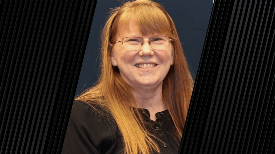 woman with long, red-blonde hair smiling and wearing a black shirt