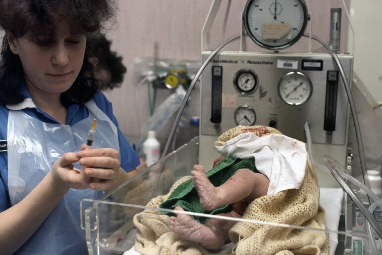 A nurse giving a VitaminK shot to a newborn baby.