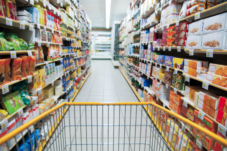 View from a shopping cart being pushed down a grocery store aisle.