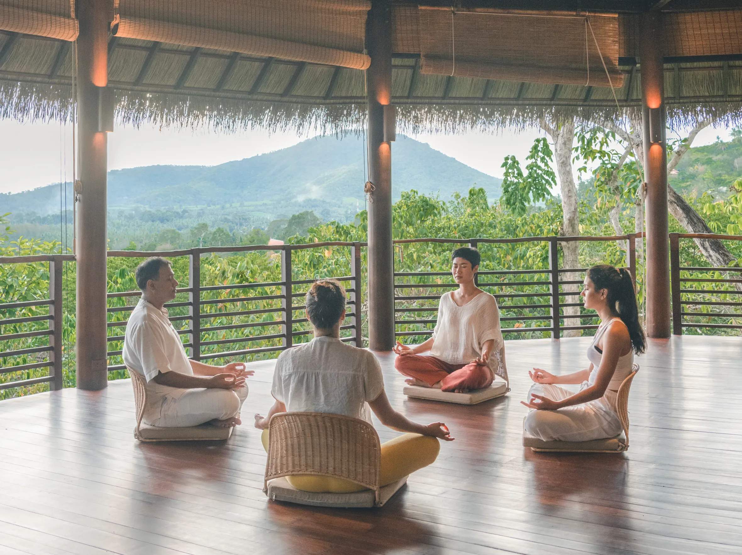 Four people meditating in a yoga pavilion at Kamalaya.
