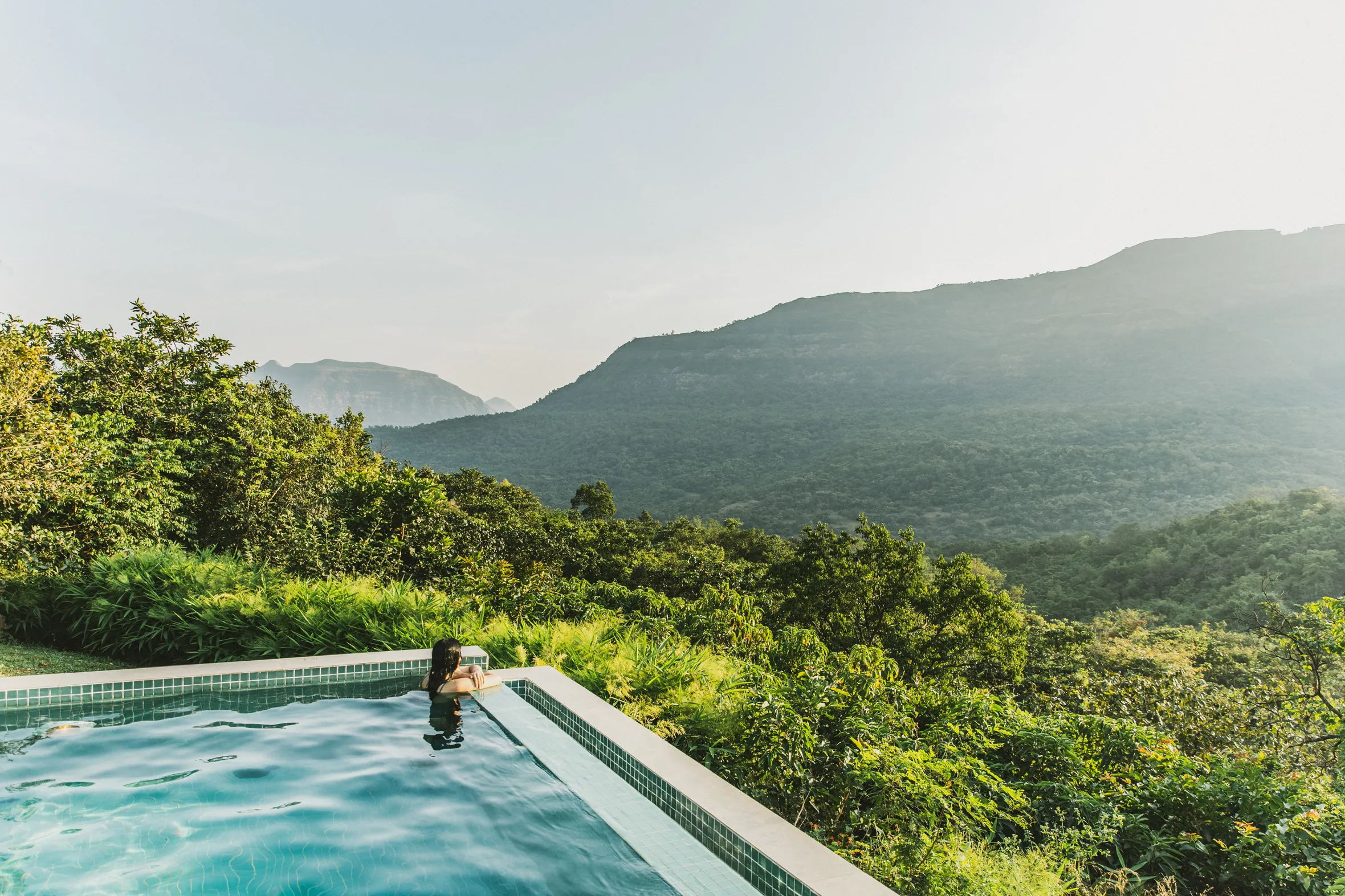 A woman in a pool overlooking forested mountains at Dharana at Shillim.