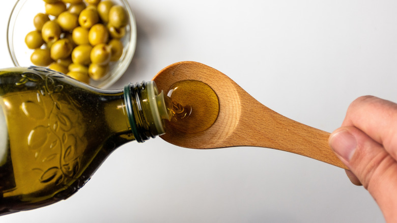 Hand pouring olive oil into spoon