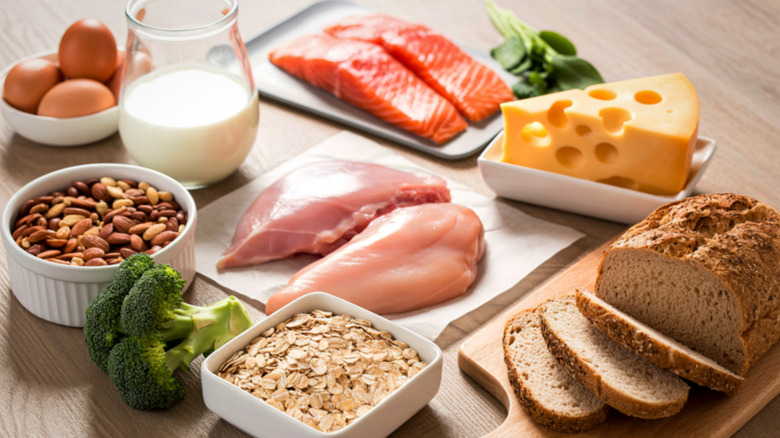 Table laid with oats, almonds, broccoli, chicken, salmon, cheese, milk, eggs and bread