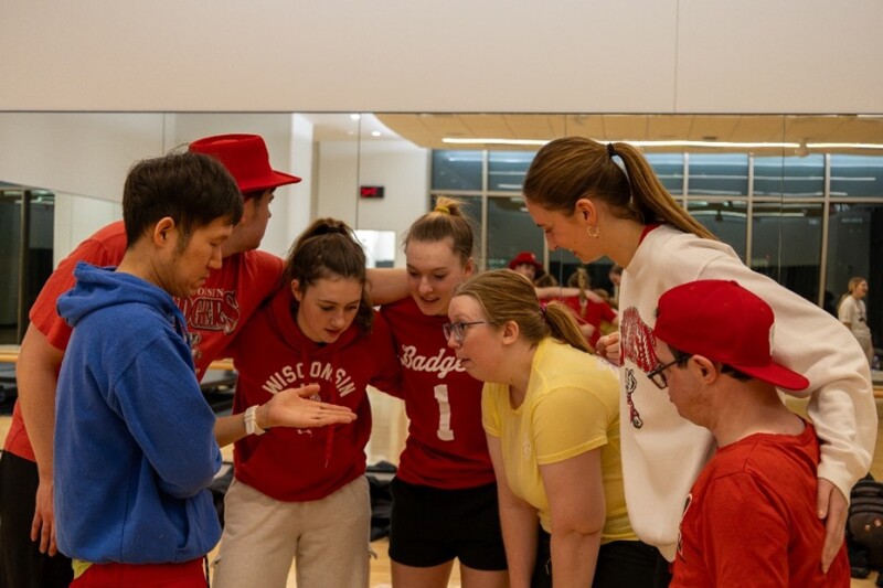 A group of people stand closely huddled together in a circle.