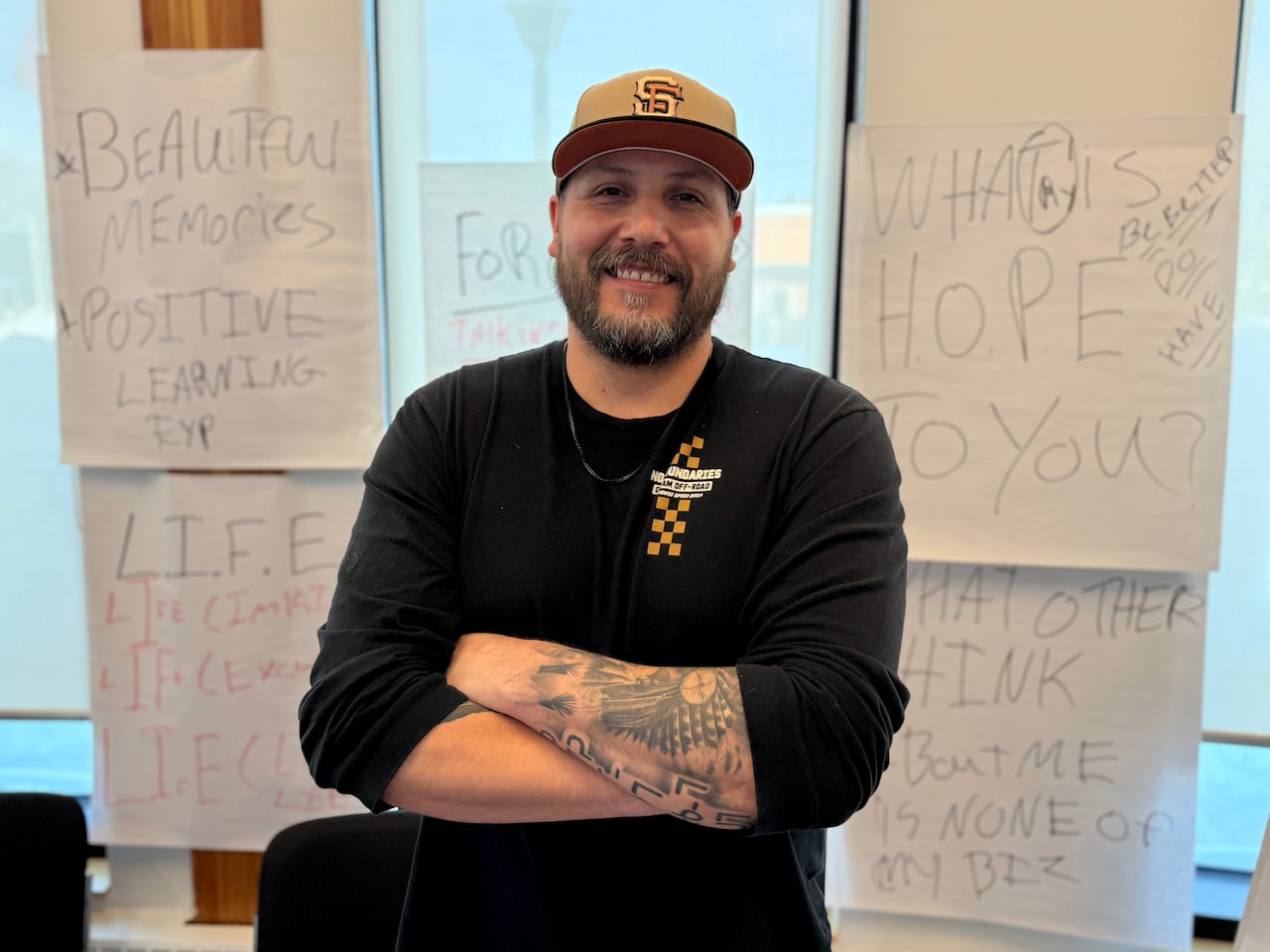 A man's arms are crossed as he smiles into the camera