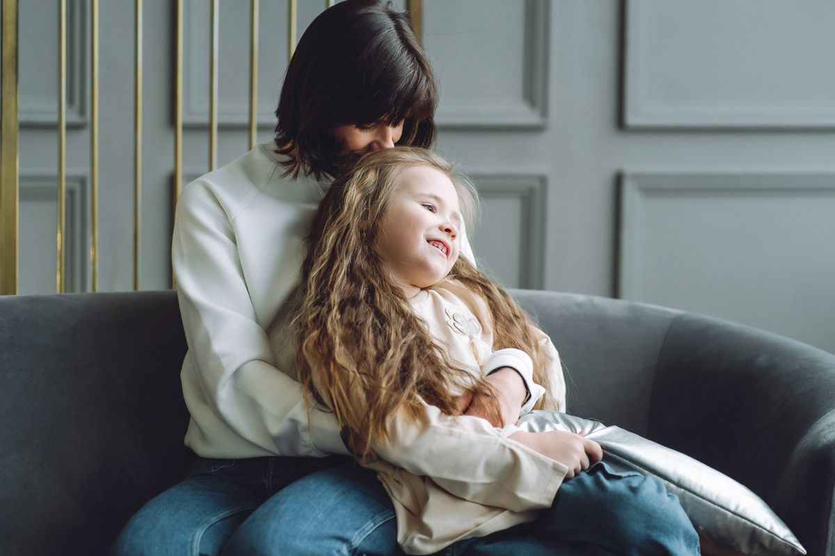 Little girl sit on mother's lap on the couch
