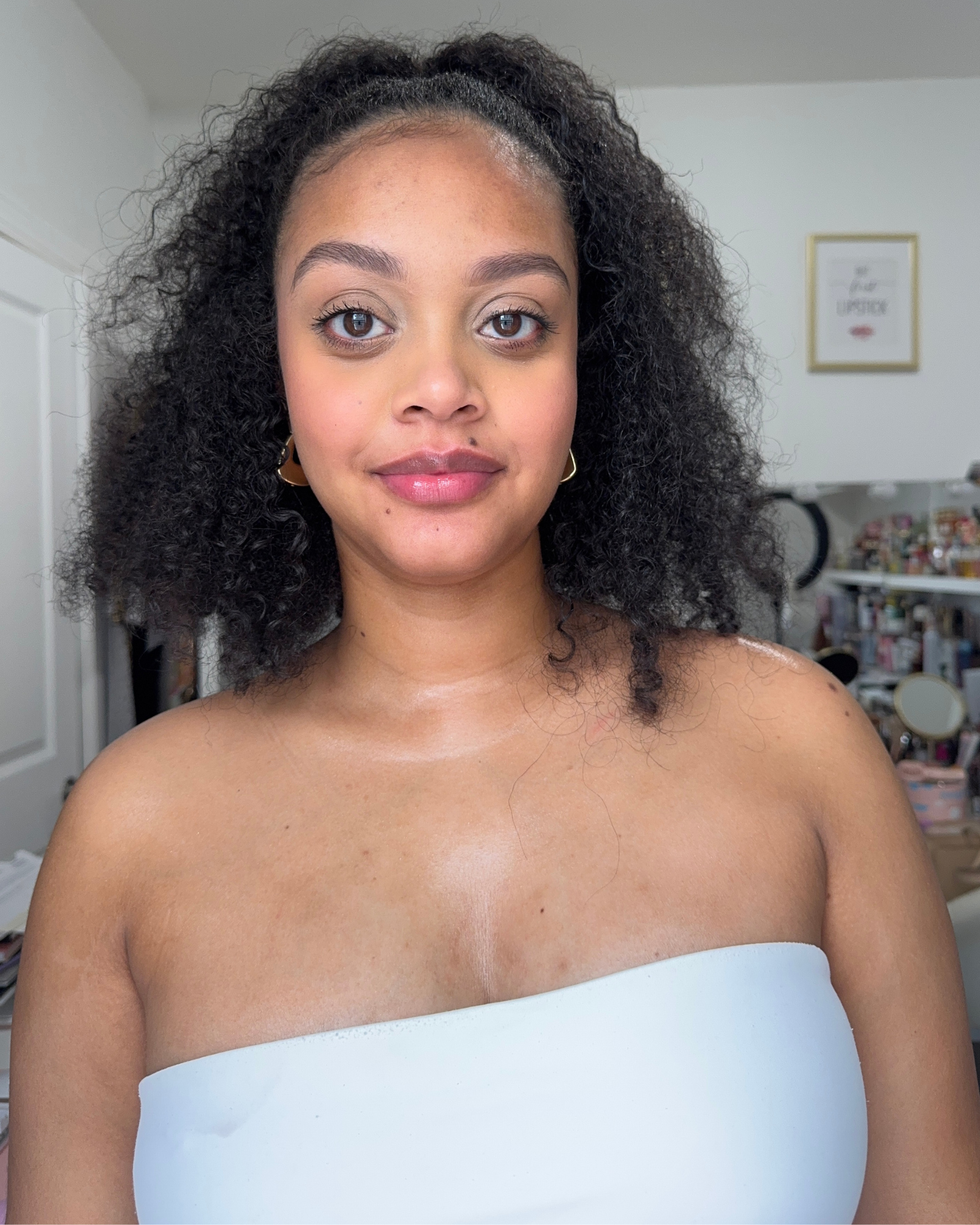 person with curly hair wearing a strapless top in a room