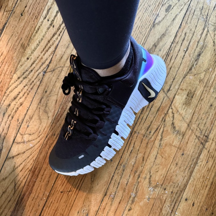 A woman’s foot wearing a black Nike Metcon training shoe.