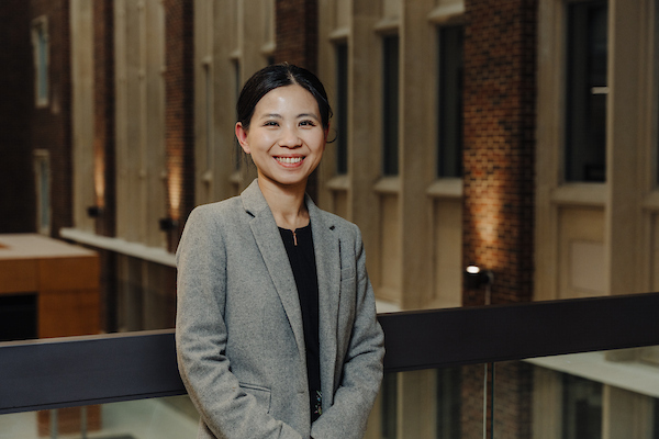 Dr. Huang standing in a blazer against a railing in a building