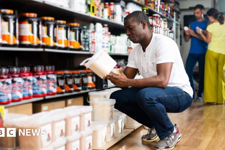 A fossil of part of a crinoid that resembles a row of teeth. The markings form a curved shape with pale, tooth‑like segments set against the darker surface of the fossil. The fossil rests on another rock in the foreground.
