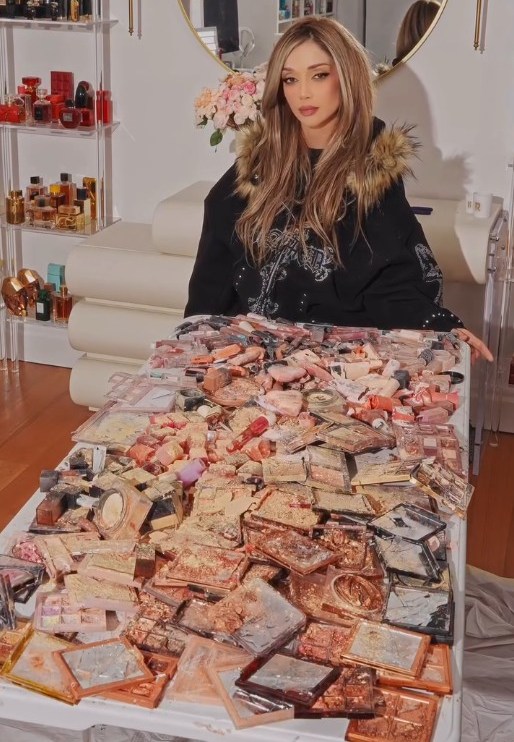 Elnaz Golrokh sits behind a table covered in smashed Huda Beauty products.