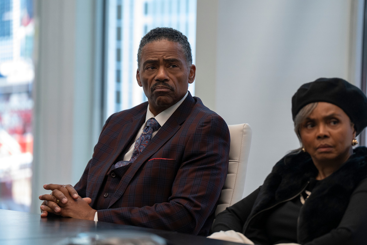 Richard Lawson as Normon and Debbi Morgan as Olivia sitting at a conference table in a modern office with large windows, appearing serious and attentive.