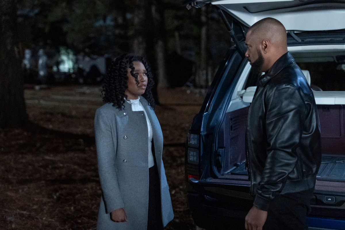 Bailey Tippen as Sylvie and Charles Malik Whitfield as Jules standing beside an open SUV trunk in a wooded area at night, having a serious conversation; woman in a gray coat, man in a black leather jacket.