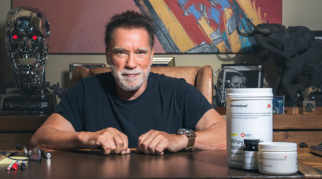 Arnold Schwarzenegger next to a bottle of Momentous supplements