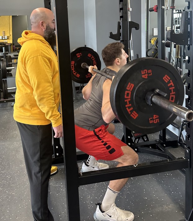 New York Golf and Fitness co-owner Mike Romano, left, observes Ben Covi as he does squats with a 135-pound barbell at the 17 Grand St. training facility in Kingston, N.Y., on Wednesday, Jan. 21, 2026. (Rick Remsnyder/Daily Freeman)