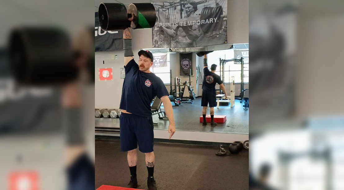Firefighter Zachary Mills performing a single arm overhead dumbbell press